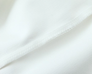Dettaglio della cucitura overlock sull'orlo interno del mini abito bianco senza schienale