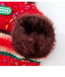 Macro shot of red knit pet sweater featuring colorful dots and a fluffy brown pom-pom