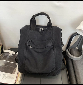 Detail shot of a black washed canvas backpack featuring double zippers and a front pocket