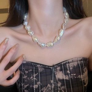 Detail of irregular baroque pearl necklace worn by a model with soft lighting focus