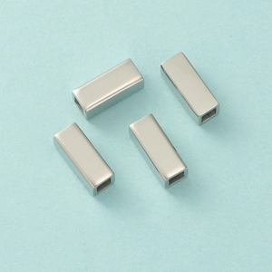 Detailed view of four silver hollow rectangular tube spacers for DIY jewelry making