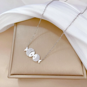 Detail of silver kissing fish pendant with frosted finish and rhinestone eye on O-chain
