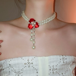 Detail of elegant double-layer pearl necklace with red floral pendant and tassels on model