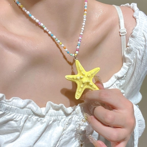 Close-up of bohemian summer necklace with colorful beads and textured yellow starfish pendant