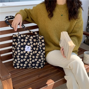 Detalle del bolso tote de pana negra con pequeños estampados de flores blancas suaves