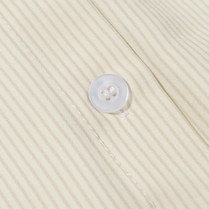 Close-up of a white four-hole button on striped cotton blend fabric showing detailed stitching
