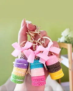 Nahaufnahme süßer Macaron-Schlüsselanhänger mit rosa Schleifen und goldener Eiffelturm