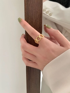 Close-up of a gold minimalist chain link ring worn by a model in elegant attire