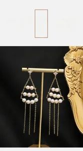 Close-up of long tassel pearl earrings with gold plating and cubic zirconia studs