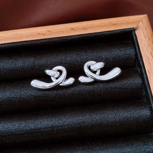 Macro shot of silver irregular twisted stud earrings on black velvet in a wooden box