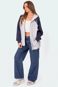 Détail d'un sweat à capuche bicolore zippé et d'un jean cargo ample à poches multiples