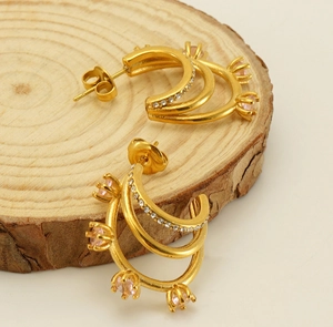 Détail de la boucle d'oreille en acier plaqué or 18k avec zircon rose sur bois