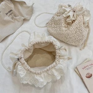 Detail of lace drawstring bucket bag with pearl strap and floral crochet pattern