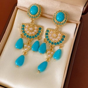 Details von Vintage-Goldohrringen mit Türkissteinen und weißen Perlen in einer Schmuckschatulle