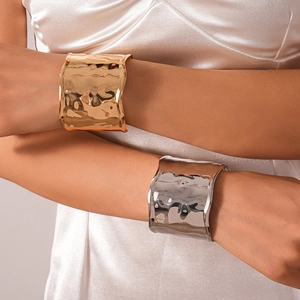 Detail showing gold and silver textured wide open bracelets worn on wrists for contrast