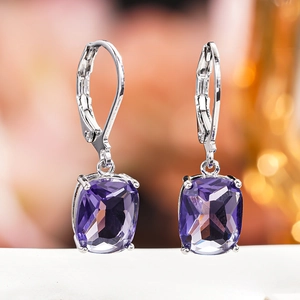 Macro shot of silver drop earrings featuring faceted purple gemstones and secure ear hooks
