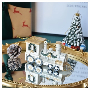 Detail of a creamy Christmas train ornament with golden accents on a festive gold tray