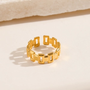 Minimalist geometric hollow-out stainless steel ring in gold finish on stone surface