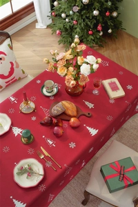 Detail of red Christmas tablecloth featuring white holiday trees and snowflake patterns
