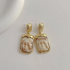 Detail of square resin stud earrings with gold hammered metal and marble texture