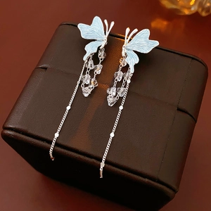 Gros plan détaillé de boucles d'oreilles argentées avec papillon bleu et cristaux