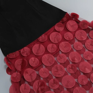 Detail of red mesh dress with black paneling and 3D circular applique decorations