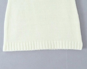 Close-up of white knit top hemline showing detailed ribbed texture and fine stitching