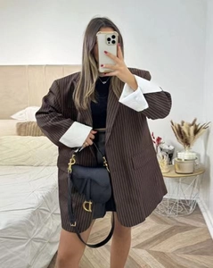 Detailed view of oversized brown striped blazer with contrasting white folded cuffs