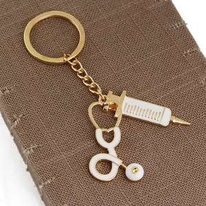Golden medical keychain featuring detailed stethoscope and syringe enamel pendants