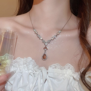 Nahaufnahme der silbernen Tropfenhalskette mit bernsteinfarbenem Stein und Diamantbesatz