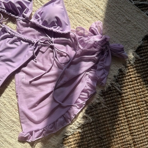 Detail of light purple three-piece bikini set with sheer mesh ruffled beach skirt