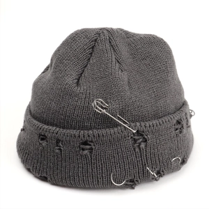 Detail of distressed grey knitted beanie with silver rings and metal safety pin accessory