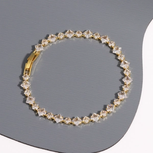 Detailed top view of a gold-toned tennis bracelet featuring clear square-cut cubic zirconia stones