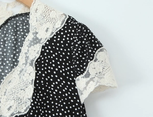 Detail of floral lace embroidery on black polka dot V-neck dress with wood hanger