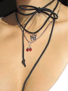 Close-up of layered necklace featuring red cherry pendant and silver butterfly charm