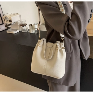 Detail of cream white pebbled leather bucket bag with a patterned wide shoulder strap