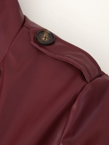Détail de l'épaulette d'un manteau en cuir bordeaux avec un bouton effet écaille de tortue