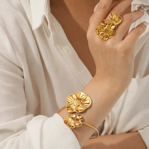 Detail of 18K gold plated flower ring and bangle set on model with brushed metal finish