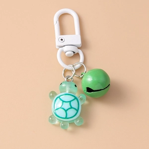 Detailed macro view of turtle keychain with green bell and polished white metal hook
