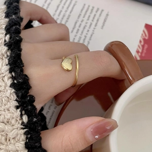 Detailed close-up of adjustable golden heart ring worn on finger in a cozy setting