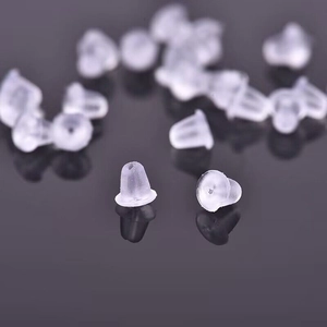 Macro shot of clear silicone earring backings with reflections on a black surface