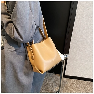 Khaki brown leather bucket bag on model featuring MACGHEE logo and vintage aesthetic