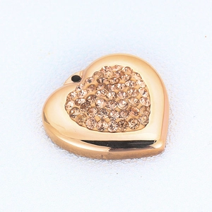 Macro shot of rose gold heart pendant with amber crystal pave setting on textured surface