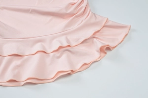 Detail of pink knitted fabric featuring double-layered ruffled edges on a white background