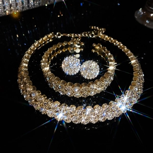 Detailed view of luxury gold-plated jewelry set with sparkling crystals on black surface