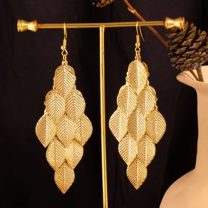 Detailed close-up of golden multi-layered leaf tassel earrings on a display stand
