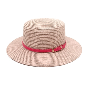 Detail of light pink woven straw hat featuring a slim red leather band and gold buckle