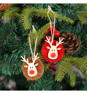 Close-up of plush reindeer ornaments with wooden faces hanging on a Christmas tree