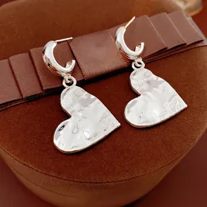Silver-colored textured heart pendant C-shape earrings displayed on a dark velvet jewelry box