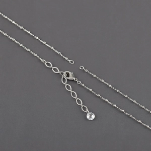 Macro shot of silver-plated cross chain necklace showing lobster clasp and faceted bead